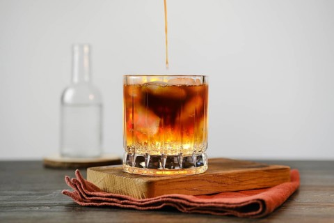 Pouring espresso in glass with tonic and ice cubes