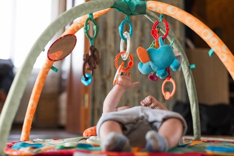 Baby lying developing rug with mobile educational toys