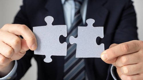 Businessman holding two puzzle pieces