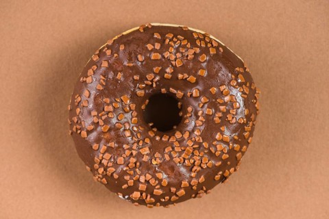 Dark chocolate doughnut with sprinkles brown background