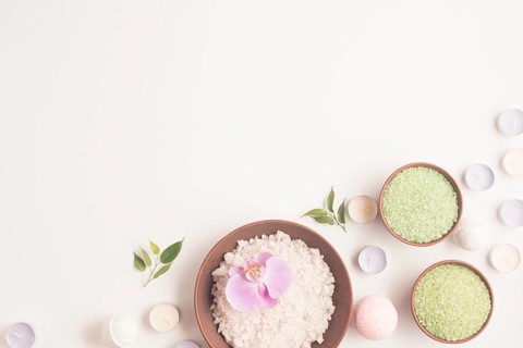 Green white herbal sea salt with many small candles white backdrop