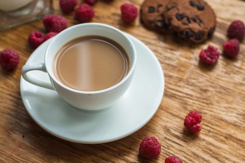 White cup coffee with chocolate cookies raspberries wooden background