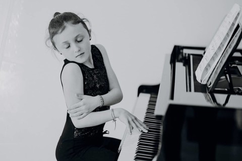 Elegant girl sits at a concert grand piano and plays the piano