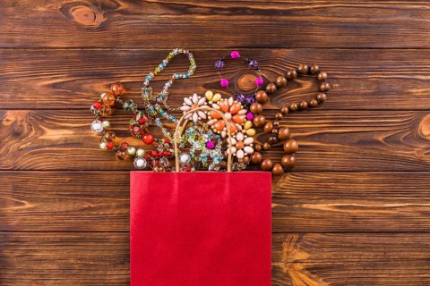 Beads jewelry red paper bag wooden background