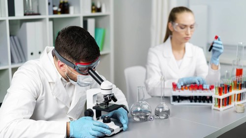 Female researcher male colleague laboratory with test tubes safety glasses