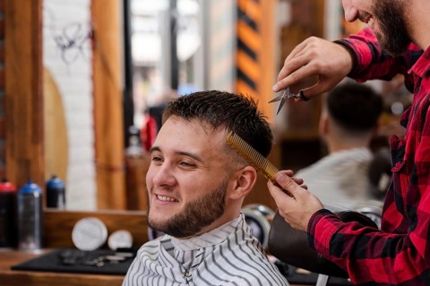 Young man trimming with scissors comb