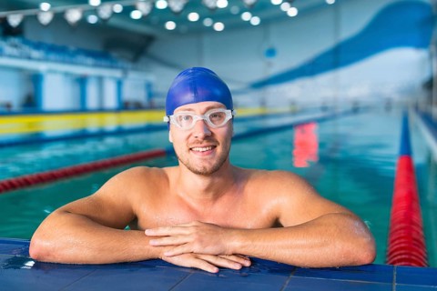 Male swimmer standing edge pool
