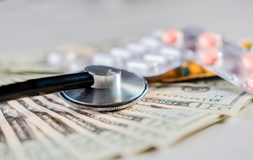 Close up of stethoscope with pills on dollar bills. High cost of medical health with stethoscope. Stethoscope with medicines on dollar bills