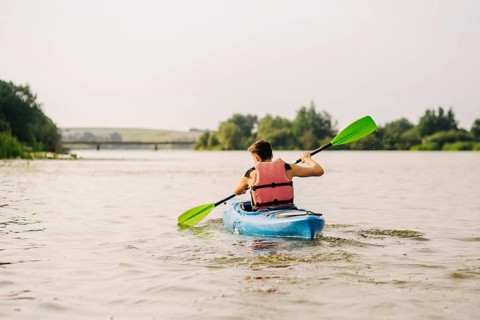 Man kayaking lake with paddle
