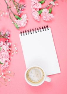 Overhead view coffee cup blank notepad with carnations gypsophila
