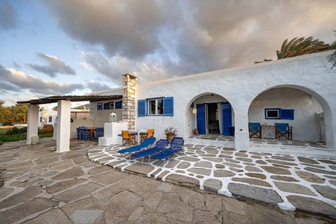 White Cycladic house with terrace with chairs and sun loungers