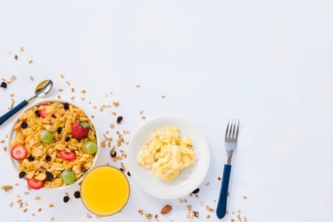 Scrambled eggs juice glass cornflakes with dried fruits white background