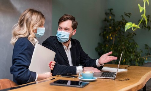 Business man woman talking about new project while wearing medical masks