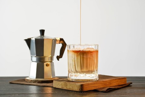 Pouring cream into coffee with ice