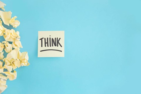 Crumpled yellow paper with think witten text adhesive note blue background