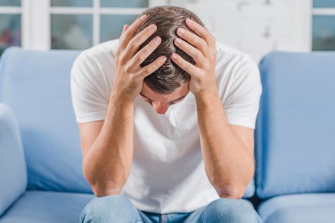 Frustrated man suffering from headache sitting sofa