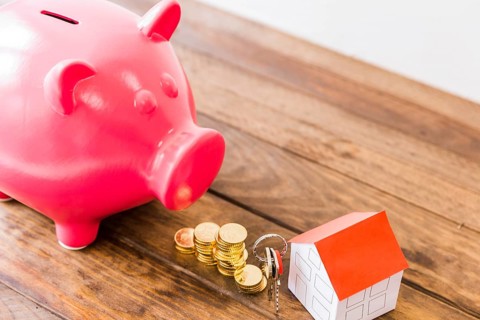 Piggybank stacked coins house key wooden desk