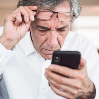 Close up serious senior man looking smart phone