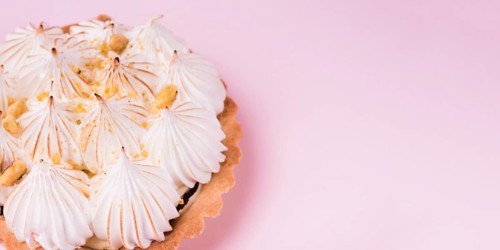 Close up lemon tart with italian meringue pink backdrop