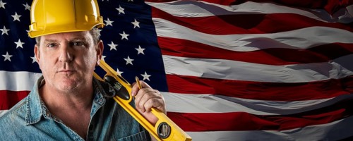 Male contractor wearing blank yellow hardhat over waving american flag background banner