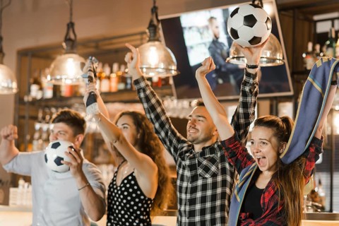 Group friends watching sport together celebrating victory bar