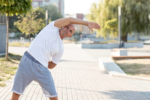 Elder man stretching sidewalk
