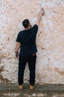 Graffiti artist painting with spray can dirty wall