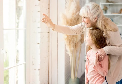 Grandma with girl home looking window