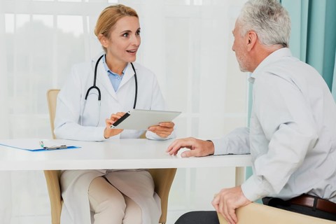 Doctor talking patient while holding tablet