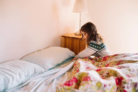 Girl arranging bedsheet bedroom