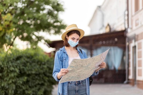 Traveller with hat medical mask checking map