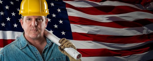 Male contractor wearing blank yellow hardhat over waving american flag background banner