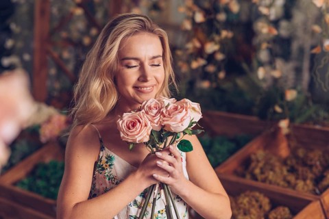Close up young woman smelling pink roses
