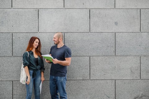 Man woman standing against gray wall