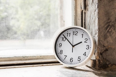Close up small white round clock near glass window
