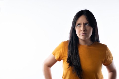 Young latin woman frowns and looks up to the left. Studio portrait on white background. Horizontal format