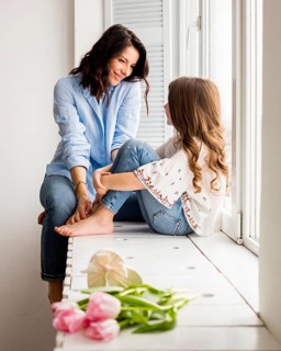 Happy mother daughter sitting window sill
