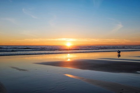 Atlantic ocean sunset with photographer silhouette taking images of surging waves at Fonte da Telha beach
