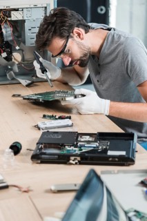 Male technician repairing computer motherboard wooden desk