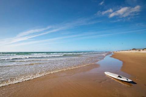 Sandy Atlantic ocean beach with surfboard at Fonte da Telha beach