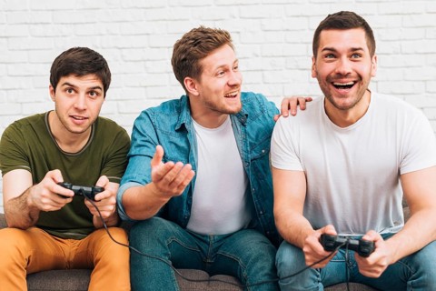 Three male friends sitting together enjoying video game