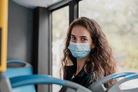 Woman with curly hair wearing medical mask bus