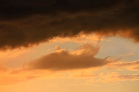 Cloudy sky at sunset. The sky is visible through a gap in the clouds. The image conveys a mood of an impending storm or bad weather