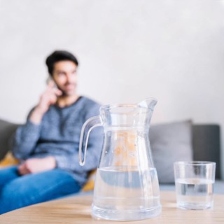 Glass jug near man with smartphone