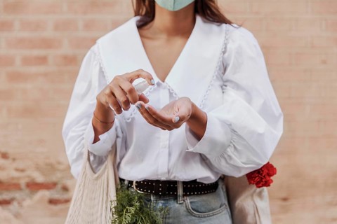 Front view woman with face mask using hand sanitizer