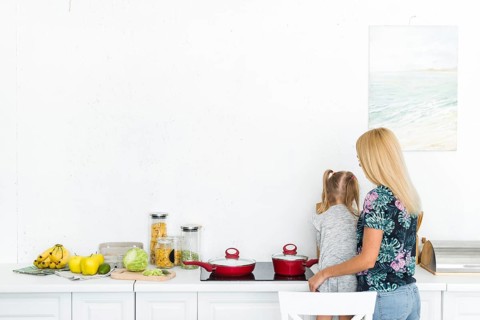 Rear view woman with her daughter kitchen