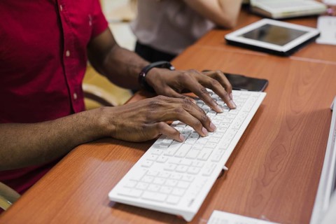 Crop black man typing keyboard