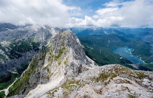 View from the summit of the Waxenstein over the rocky and narrow ridge of the Waxenstein ridge to the Eibsee lake and Hoellental