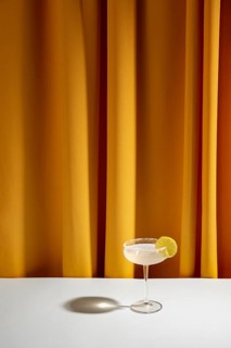 Lime cocktail saucer glass white table against yellow curtain