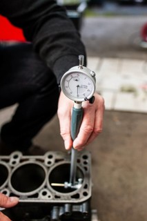 A motor vehicle assessor inspects a cylinder head of a car engine